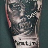 Awesome black and white crazy maniac face tattoo with lettering on arm