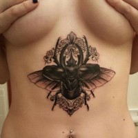 Tatuaje en el estómago, escarabajo negro en el encaje