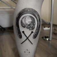Awesome black ink horseshoe with skull and nails tattoo on leg