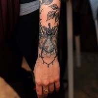 Tatuaje en la muñeca, escarabajo con joya y hojas