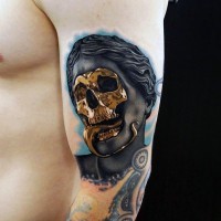 Awesome designed little mystical statue with golden skeleton tattoo on arm