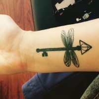 Awesome dragonfly shaped black ink on wrist tattoo of mystic key