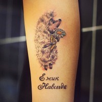 Arm Tattoo mit erschütterndem grauem Zeichentrickigel mit Kamille und Inschrift 
