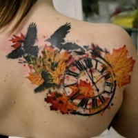 Tatuaje en el hombro, reloj con hojas amarillas y cuervos