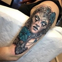 Tatuagem braço colorido impressionante olhar de máscara mística com flores pintadas por Jenna Kerr
