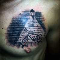 Tatuaje en el pecho,  bicicleta con farol en la pared de ladrillos