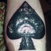Tatuaje en el brazo, rostro de hombre demoniaco en símbolo de naipes
