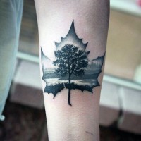 Tatuaje en el antebrazo, hoja de arce estilizada con árbol