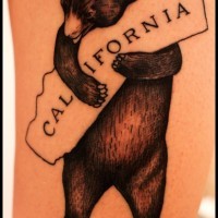 Tatuaje de oso que llave un letrero