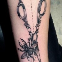 Beautiful black and white big antic scissors with insect tattoo on arm