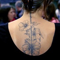 Schöne Hibiskus Blumen und hebräische Inschrift Tattoo am Rücken