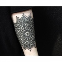 Beautiful little black ink Hinduism style flower tattoo on arm