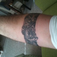 Beautiful ornamented gray-ink band tattoo on forearm