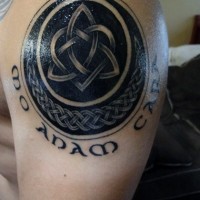 Big black and white Celtic symbol tattoo on shoulder with lettering