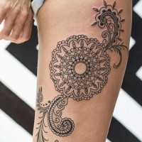 Big black and white tribal style flower with ornaments tattoo on thigh