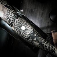 Big black ink mystical designed hypnotic symbol on sleeve combined with various geometrical ornaments