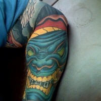 Großes Tattoo von blauem schreckhaftem lachendem Monster am Unterarm