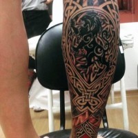 Tatuaje en la pierna, emblema negra de león, estilo celta