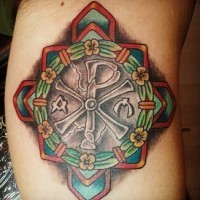 Big detailed colorful cross tattoo on arm stylized with flowers and Chirho