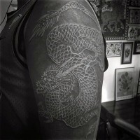 Tatuaje en el brazo,
dragón estilizado blanco en el fondo negro