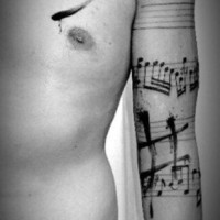 Tatuaje en el brazo, notas musicales diferentes, tinta negra idea estupenda