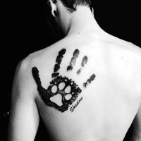 Big incredible looking black ink scapular tattoo of human hand stylized with dog paw print and lettering