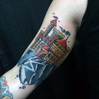 Tatuaje en el brazo,
castillo multicolor en el acantilado