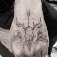 Big old looking hand tattoo of various animal skulls and arrow