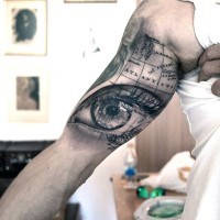 Big realistic looking woman eye with nautical map tattoo on arm