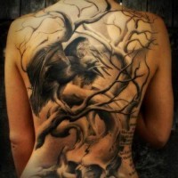 Tatuaje en la espalda de un árbol que crece en una calavera con cuervos.
