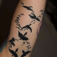 Tatuaje en el antebrazo,
bandada de aves de color negro
