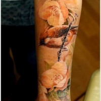 Tatuaje en el brazo, pájaro y flores suaves