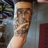 Black and gray style big biceps tattoo of Buddha statue with lotus flower
