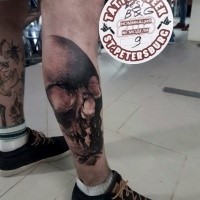 Black and gray style colored leg tattoo of human skull