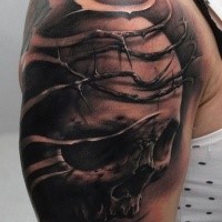 Black and gray style colored shoulder tattoo of human skull with vine