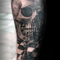 Black and gray style detailed forearm tattoo of human skull with chess figure