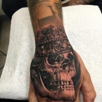 Black and gray style detailed hand tattoo of king skull