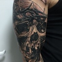 Black and gray style detailed hand tattoo of human skull with vine