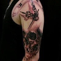 Black and gray style detailed shoulder tattoo of human skull and clock