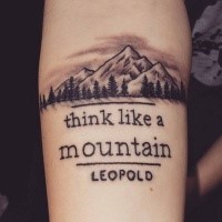 Black and gray style forearm tattoo of mountain with lettering