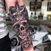 Black and gray style human skull with crown tattoo on forearm