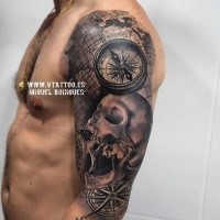 Black and gray style shoulder tattoo of human skull with compass and map