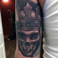 Black and gray style skull tattoo on arm with crown