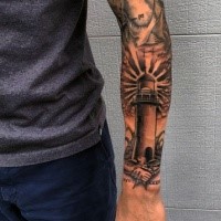 Schwarzes und graues Tattoo mit  kleinem Leuchtturm auf Unterarm