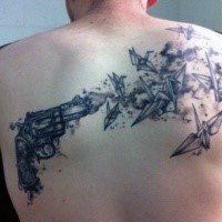 Black and gray style upper back tattoo of small pistol and paper birds