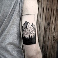 Black and white arm tattoo of mountains with forest