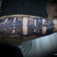 Black and white forearm tattoo of number stylized with city sights and lettering