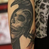 Schwarze Krähe auf einem Ast mit großem menschlichem Schädel detailliertes im alten Stil Unterarm Tattoo