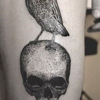 Tatuaje en el muslo,  cuervo en el cráneo humano, tinta negra