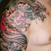Black dragon with red eyes in japanese style tattoo on shoulder